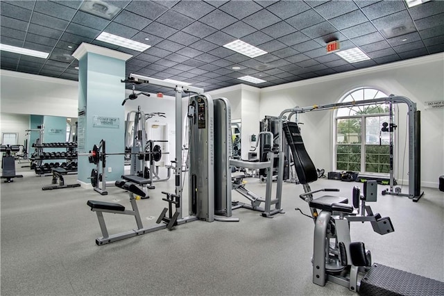 exercise room featuring ornamental molding, a drop ceiling, and baseboards