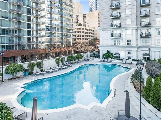 community pool featuring a view of city, a patio, and fence