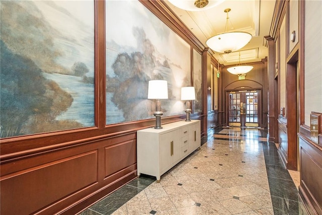 hallway with a decorative wall, a wainscoted wall, granite finish floor, french doors, and ornamental molding