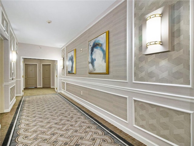 hallway with wainscoting and a decorative wall