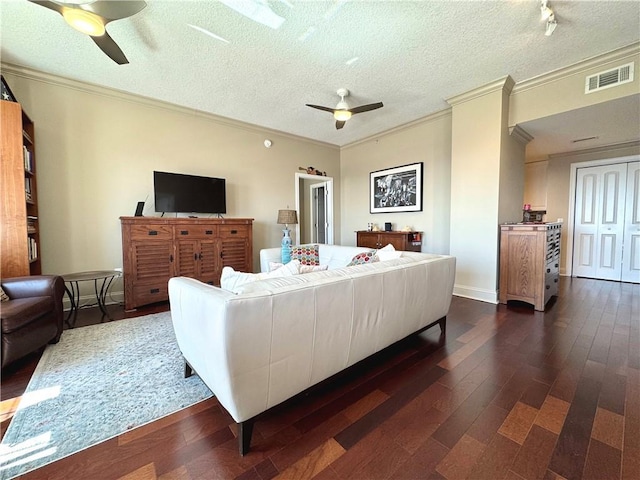 living room with a textured ceiling, dark wood-style flooring, visible vents, a ceiling fan, and ornamental molding