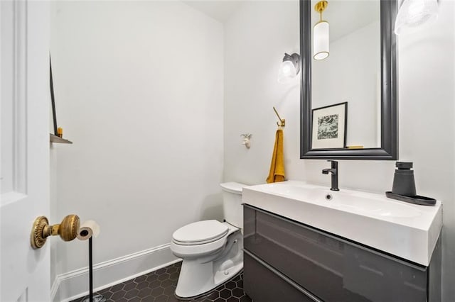 bathroom with toilet, vanity, and baseboards