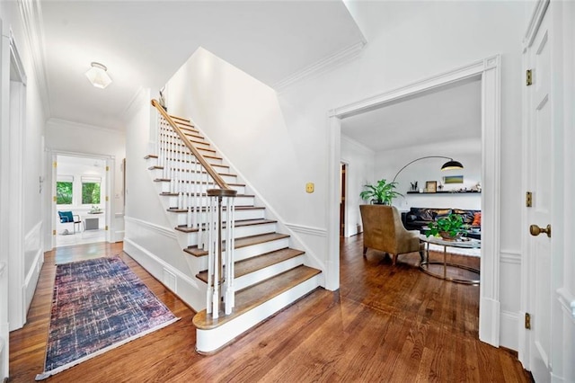 stairs with ornamental molding and wood finished floors