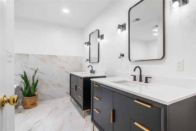 bathroom with marble finish floors, two vanities, and recessed lighting