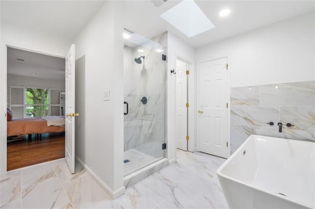 ensuite bathroom featuring marble look tile flooring, a skylight, a marble finish shower, a freestanding tub, and baseboards