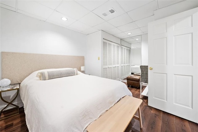 bedroom with wood finished floors, a closet, recessed lighting, and a paneled ceiling