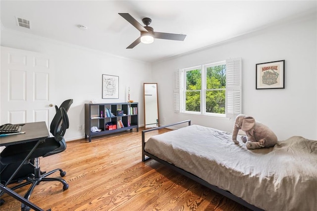 bedroom featuring light wood finished floors, crown molding, ceiling fan, a desk, and baseboards