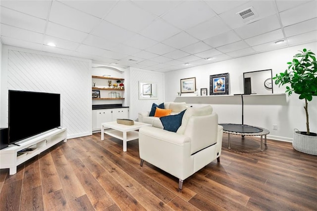 living area featuring wood finished floors, a drop ceiling, baseboards, and recessed lighting