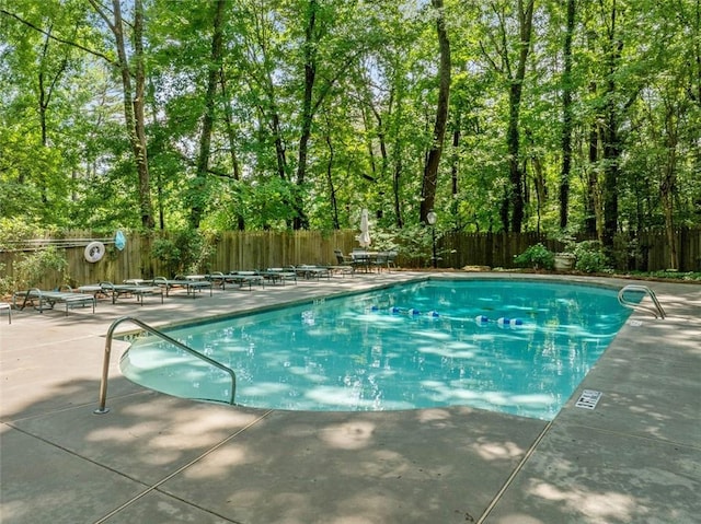 community pool with a patio area and a fenced backyard