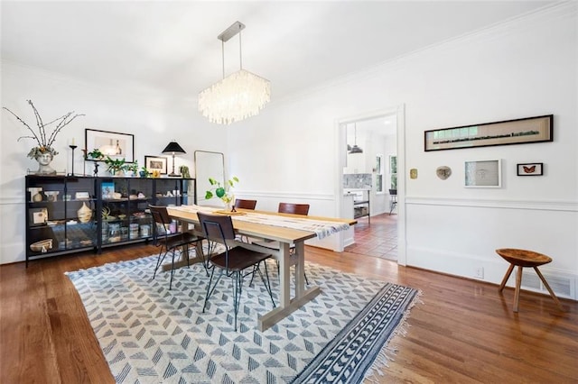 dining room featuring a chandelier, ornamental molding, and wood finished floors