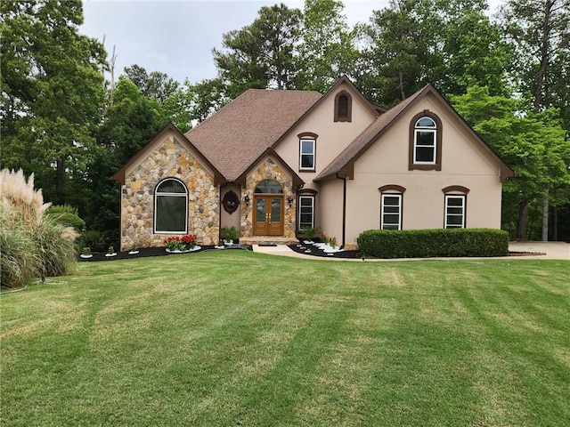 french country style house with french doors, a front lawn, stone siding, and stucco siding