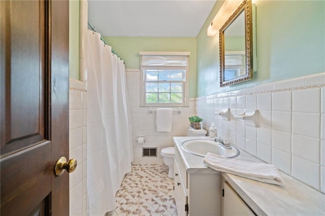 bathroom with toilet, a shower with shower curtain, vanity, and tile walls