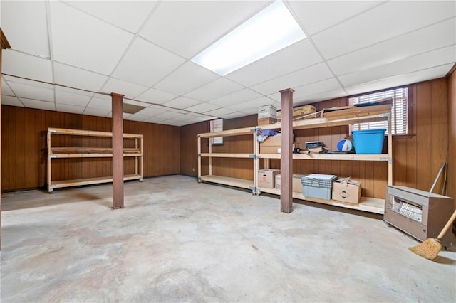 basement featuring wood walls and a drop ceiling