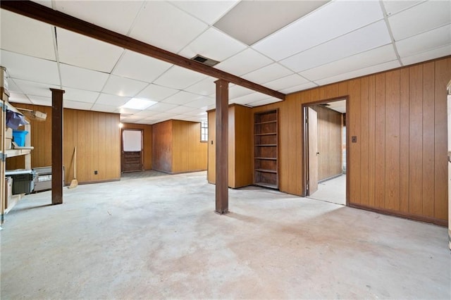 basement with a paneled ceiling and wood walls