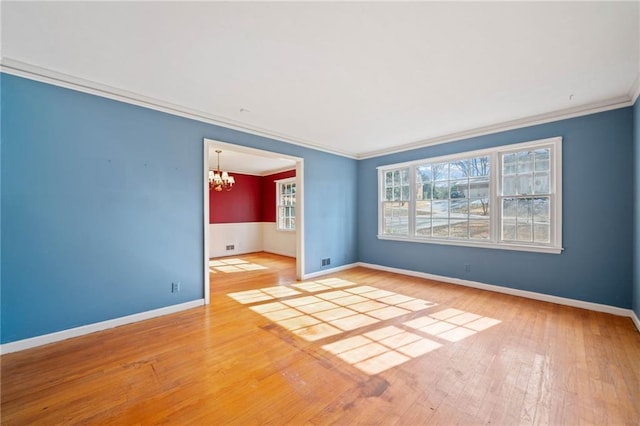 empty room with hardwood / wood-style floors, crown molding, and a chandelier