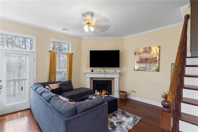 living room with a tile fireplace, ceiling fan, dark hardwood / wood-style floors, and ornamental molding