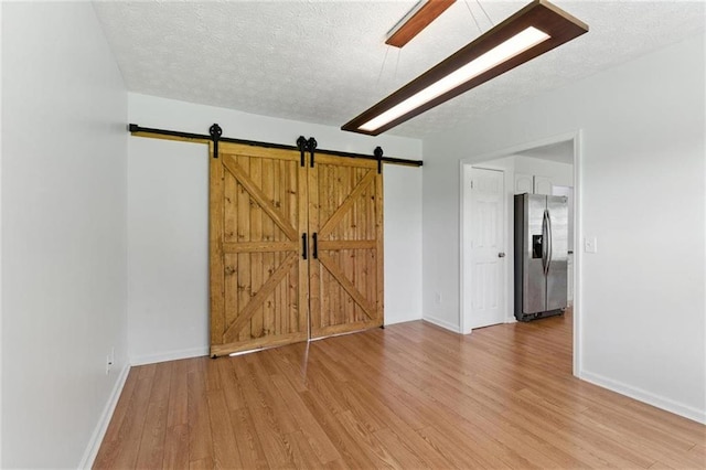 150 Crestworth Xing, Powder Springs, GA 30127 - spare room featuring a textured ceiling, light wood-type flooring, and a barn door