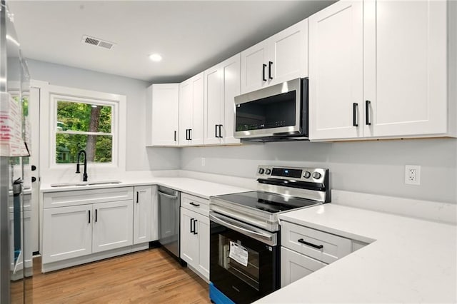 163 Oakcliff Ct, South Fulton, GA 30331 - kitchen featuring stainless steel appliances, a sink, light countertops, white cabinets, and light wood-style flooring