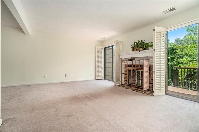 unfurnished living room featuring carpet floors, a tile fireplace, visible vents, and baseboards