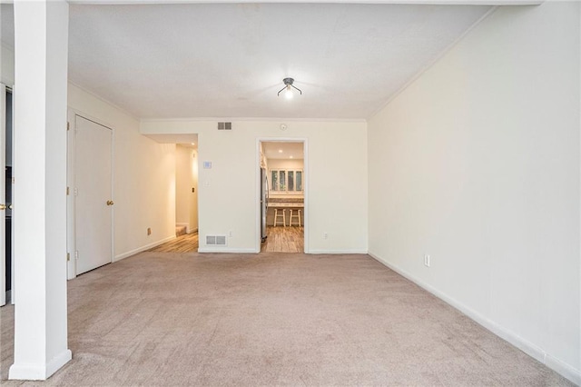 unfurnished bedroom with baseboards, freestanding refrigerator, visible vents, and light colored carpet