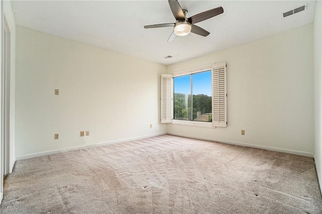 spare room featuring a ceiling fan, visible vents, light carpet, and baseboards