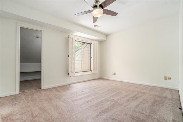 empty room featuring light carpet, ceiling fan, visible vents, and baseboards