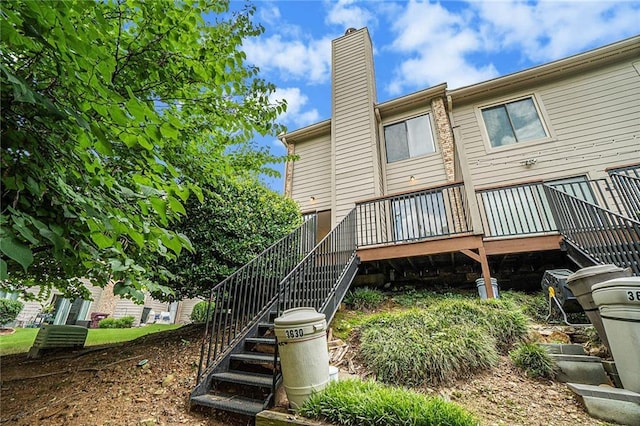 rear view of house with stairs, a chimney, and a deck