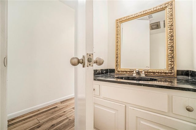 bathroom with wood finished floors, vanity, and baseboards