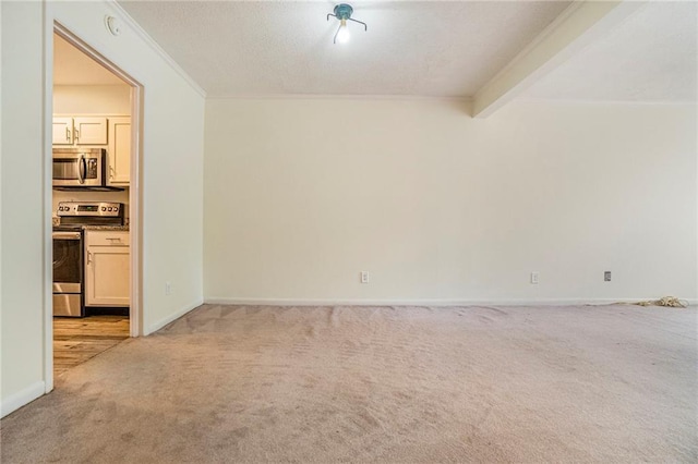 spare room with beam ceiling, light colored carpet, crown molding, and baseboards