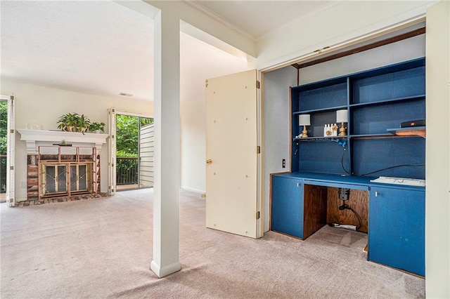 unfurnished office featuring carpet, crown molding, and a glass covered fireplace