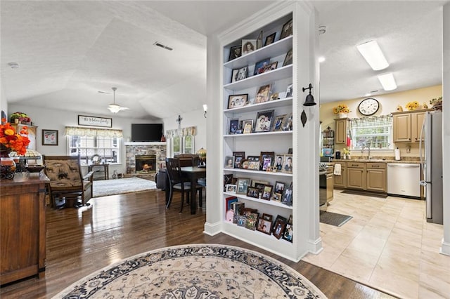 interior space featuring lofted ceiling, a textured ceiling, visible vents, a sink, and light wood-style floors