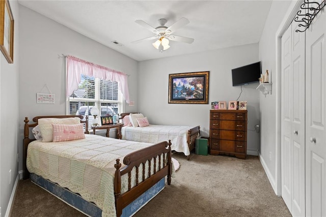 carpeted bedroom with a closet, visible vents, baseboards, and ceiling fan