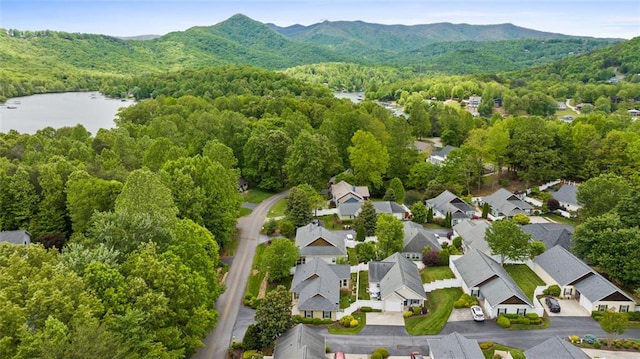 aerial view with a water and mountain view, a wooded view, and a residential view