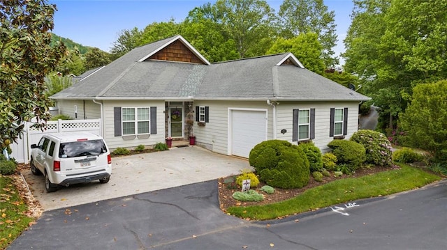 view of front of house featuring fence, an attached garage, a shingled roof, and concrete driveway