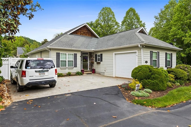 view of front of home featuring roof with shingles, a garage, fence, and aphalt driveway