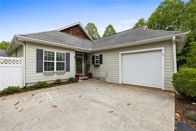 ranch-style home featuring a shingled roof, driveway, fence, and an attached garage