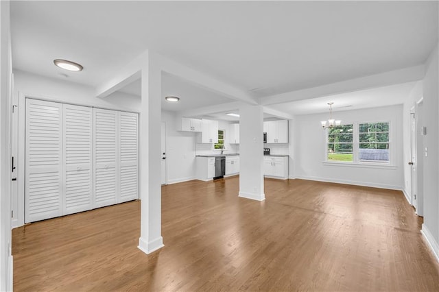 unfurnished living room featuring an inviting chandelier and light hardwood / wood-style flooring