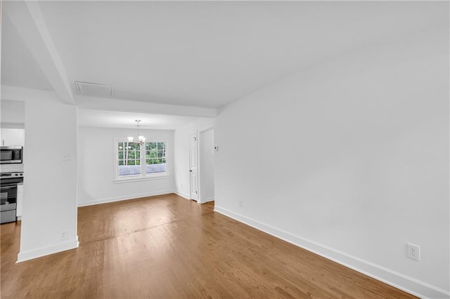 unfurnished living room featuring an inviting chandelier and light hardwood / wood-style floors