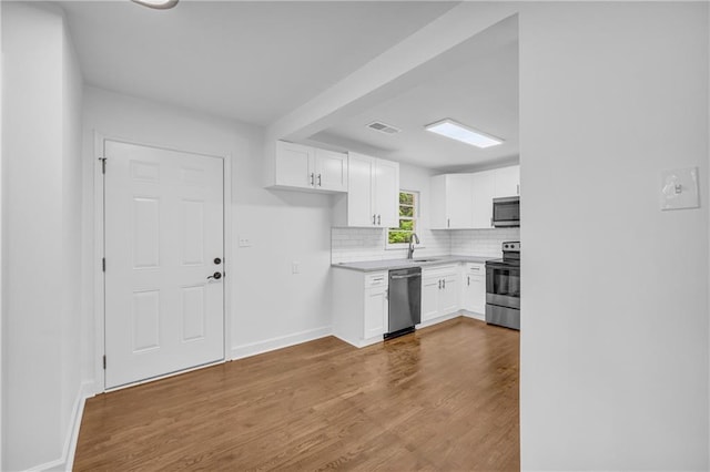 kitchen featuring light hardwood / wood-style flooring, sink, backsplash, white cabinets, and appliances with stainless steel finishes