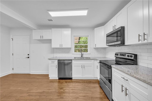 kitchen with white cabinets, light hardwood / wood-style floors, appliances with stainless steel finishes, and sink