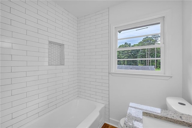 full bathroom with tiled shower / bath, vanity, and toilet