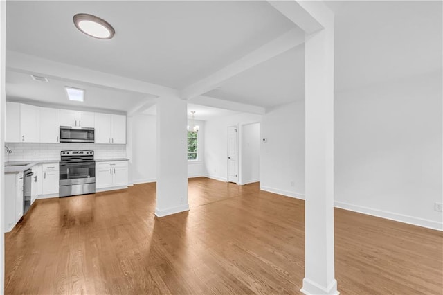 kitchen with stainless steel appliances, backsplash, light wood-type flooring, and white cabinetry