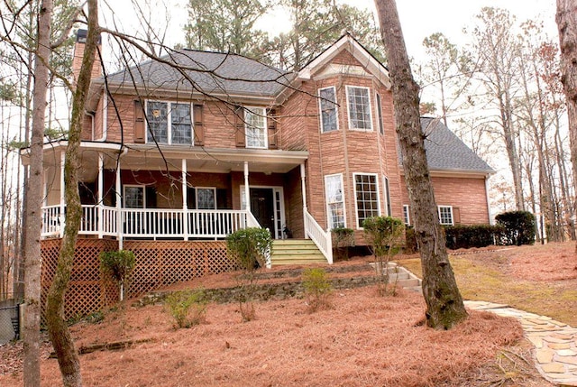 view of front of property featuring covered porch, a shingled roof, and a chimney