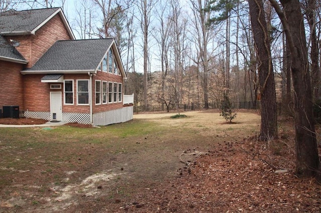 view of yard with entry steps, fence, and central AC