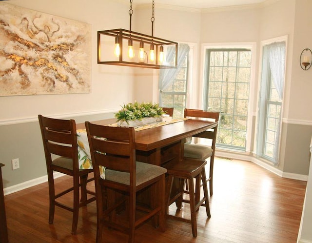 dining space with crown molding, baseboards, and wood finished floors