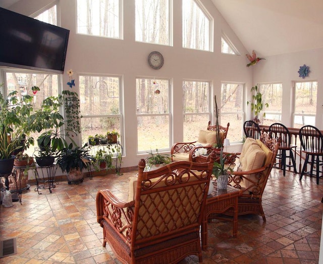 sunroom with a healthy amount of sunlight, visible vents, and vaulted ceiling