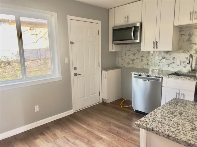 kitchen with white cabinetry, stainless steel appliances, light stone countertops, and sink