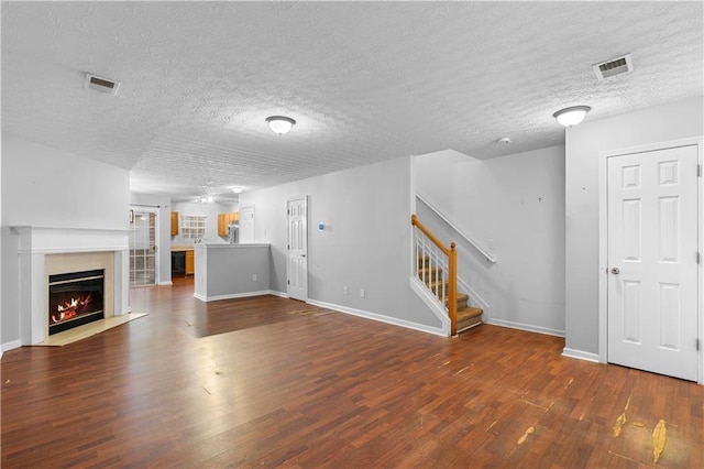 unfurnished living room with a textured ceiling and dark wood-type flooring