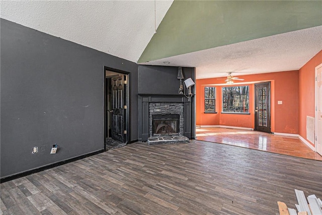 unfurnished living room featuring ceiling fan, hardwood / wood-style floors, a textured ceiling, and a fireplace