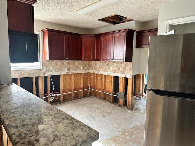 kitchen featuring decorative backsplash, a textured ceiling, and stainless steel refrigerator